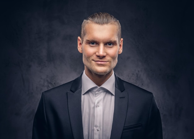 Free photo a stylish handsome caucasian man posing and looking at camera isolated on a dark background.