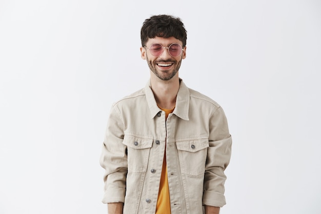 Free photo stylish handsome guy posing against the white wall with sunglasses