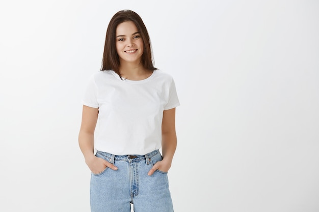 Stylish happy young woman posing against white wall