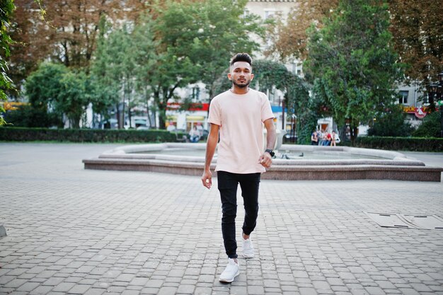 Stylish indian beard man at pink tshirt India model posed outdoor at streets of city