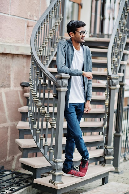 Stylish indian man at glasses wear casual posed outdoor against iron stairs