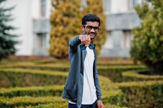 Stylish indian man at sunglasses wear casual posed outdoor and show double glass of glasses