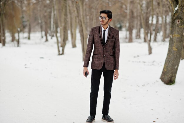 Stylish indian student man in brown suit and glasses posed at winter day outdoor