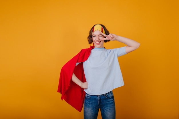 Free photo stylish lady in funny paper crown posing with peace sign