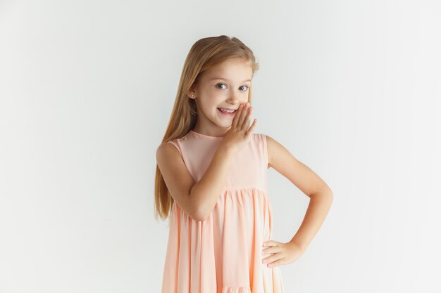 Stylish little smiling girl posing in dress isolated on white studio