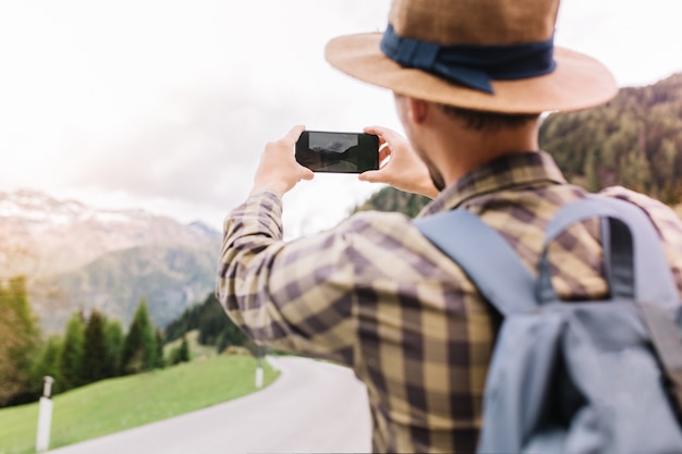 Free photo stylish male traveler exploring italy and taking picture of beautiful nature views holding his smartphone