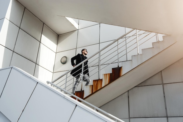 Stylish man in back coat going upstairs Minimalizm style