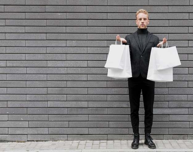 Free Photo stylish man in black with white shopping bags