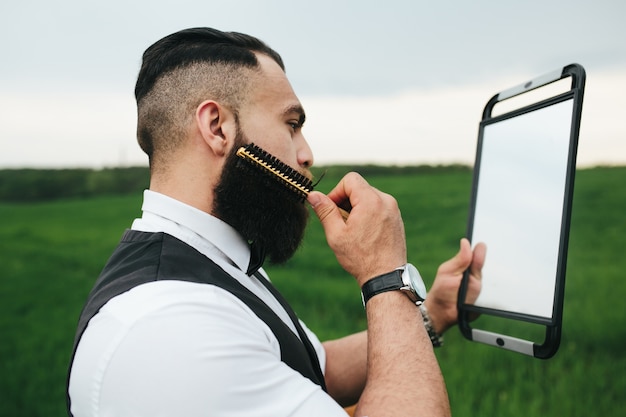 Free photo stylish man combing his beard