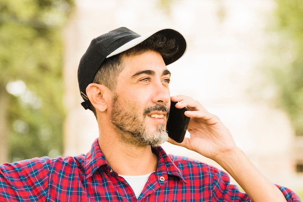 Free photo stylish man wearing black cap on his head talking on mobile phone