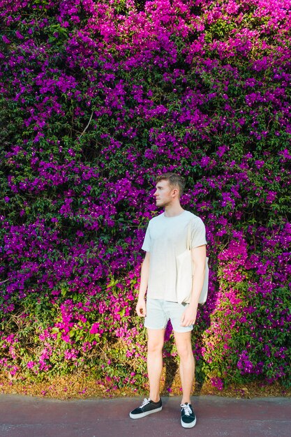 Stylish man with cloth bag standing in park looking away