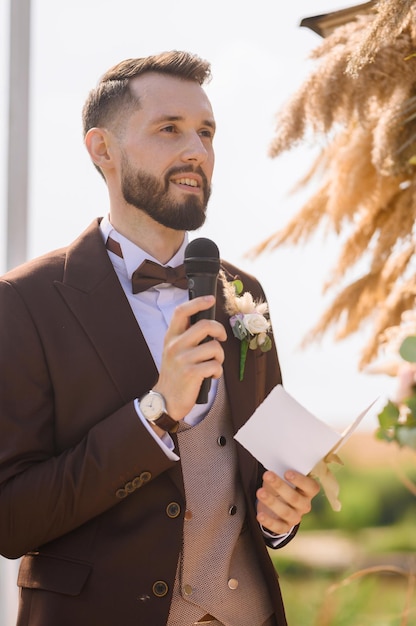 Stylish man with microphone talking speech on wedding day