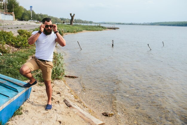 Stylish man with sunglasses posing by the lake