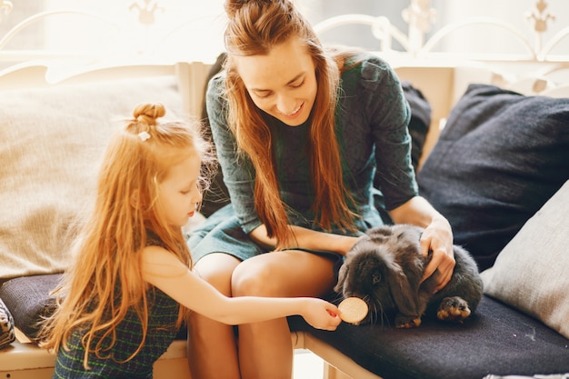 stylish mother with long hair and a green dress playing with her little cute daughter