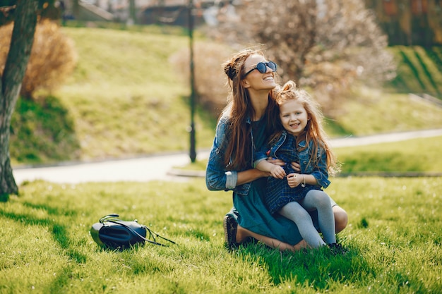 stylish mother with long hair and a jeans jacket playing with her little cute daughter