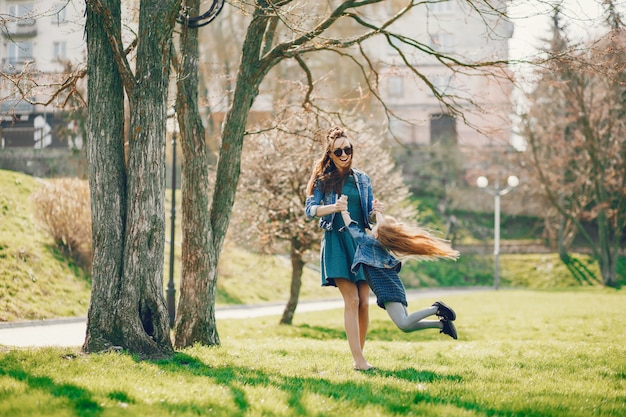 stylish mother with long hair and a jeans jacket playing with her little cute daughter