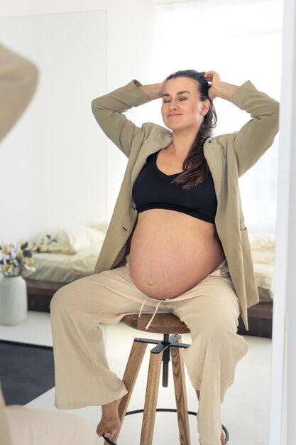 Free Photo stylish pregnant woman sitting on a chair pregnancy and style concept