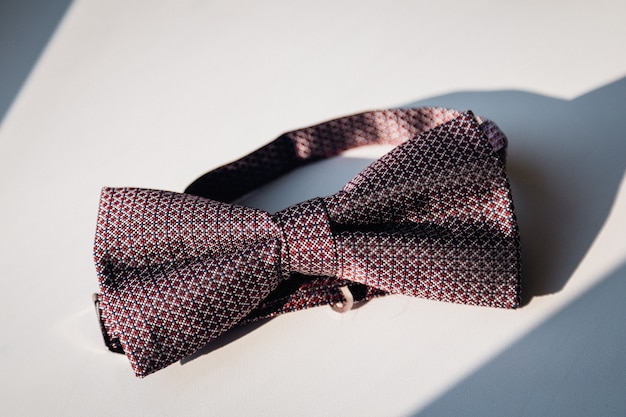 Stylish red bow tie lies in the ray of light 