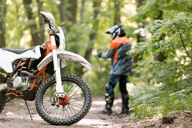 Free photo stylish rider with motorbike parked in the forrest