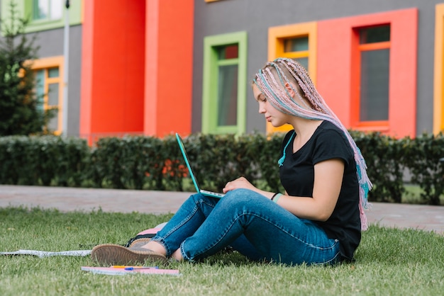 Stylish schoolgirl in park with laptop