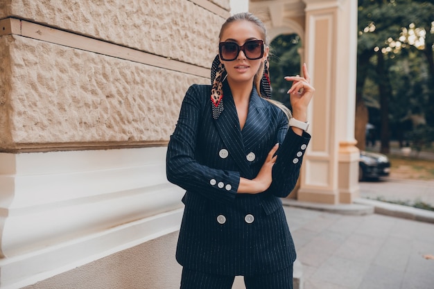 Free photo stylish sexy woman dressed in elegant tuxedo suit walking in city on summer spring day