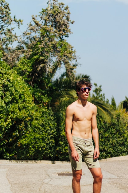 Stylish shirtless young man with eyeglasses posing at outdoors