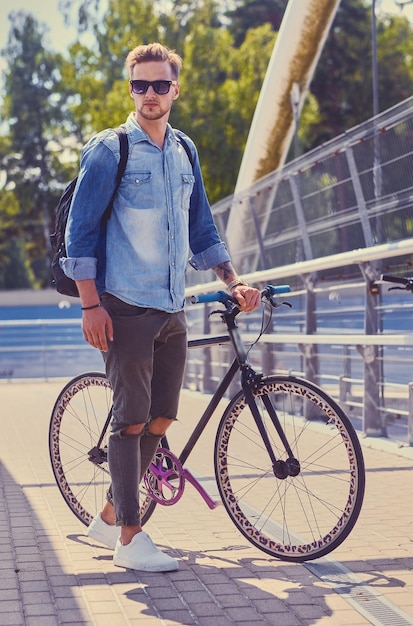 Free photo stylish single speed cyclist on a bridge.