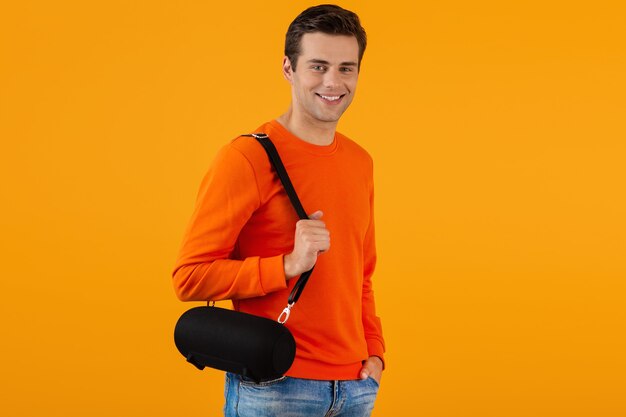 Free Photo stylish smiling young man in orange sweater holding wireless speaker happy listening to music 