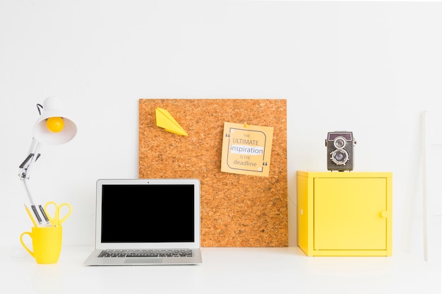 Stylish table with laptop and cork board