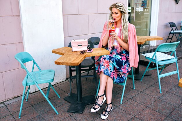 Stylish trendy fashionable woman wearing feminine elegant outfit, drinking cocktail at restaurant