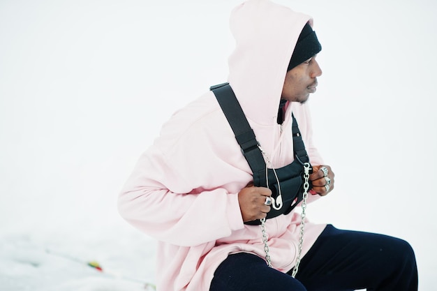 Free photo stylish urban style african american man in pink hoodie posed at frozen lake in winter