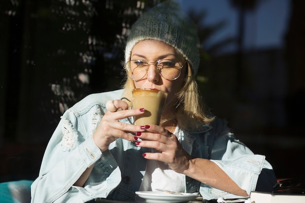 Free photo stylish woman drinking coffee in cafe