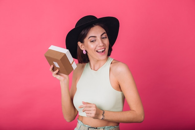 Stylish woman in hat on pink red wall