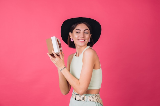 Stylish woman in hat on pink red wall