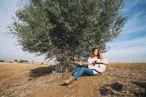 Free photo stylish woman playing guitar near bush