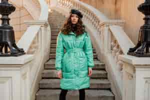 Free photo stylish woman posing in winter autumn fashion trend blue puffer coat and hat beret in old beautiful street stairs