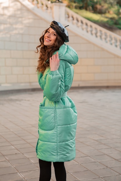 Free Photo stylish woman posing in winter autumn fashion trend blue puffer coat and hat beret in old beautiful street