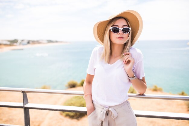 Stylish woman at the summer beach in a hot day in summer hat and sunglasses