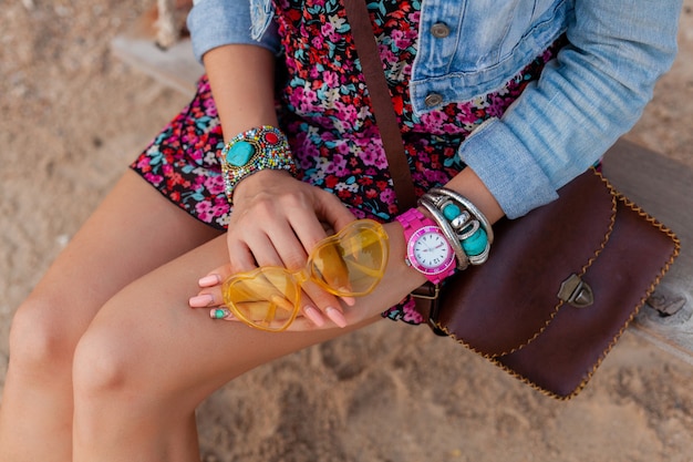 Stylish woman in vacation on beachhands with colorful yellow sunglasess accessories jewelry and bag