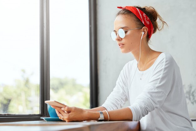 Stylish woman wearing bandana sitting in cafe