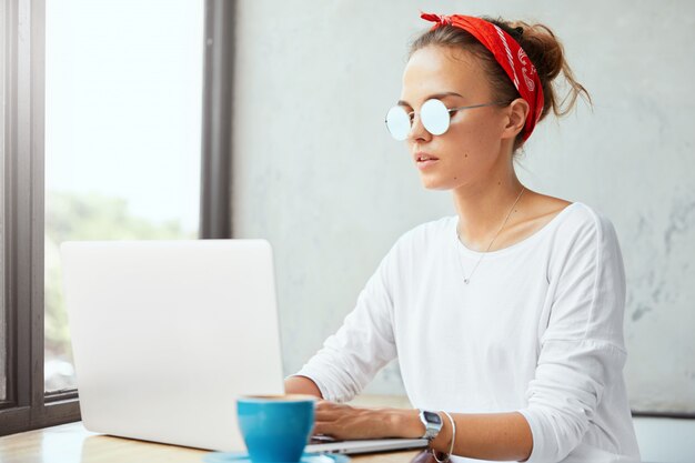 Stylish woman wearing bandana sitting in cafe