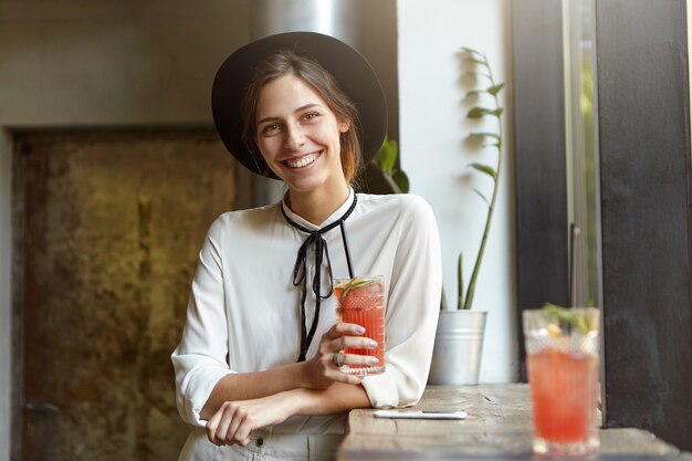 Free Photo stylish woman with big hat sitting in cafe