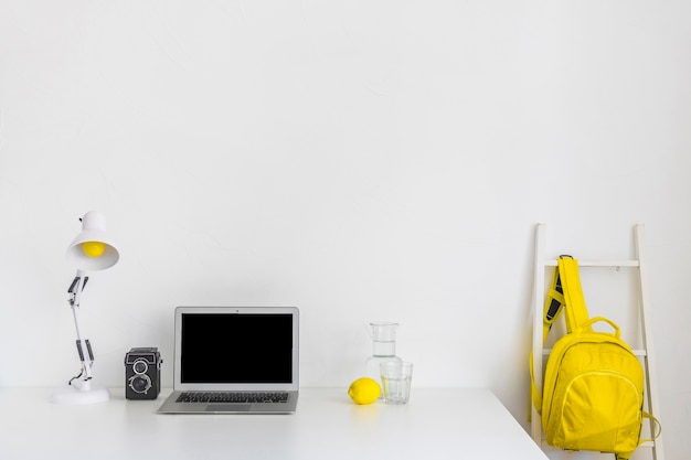 Free Photo stylish workplace in white and yellow colors with backpack and laptop