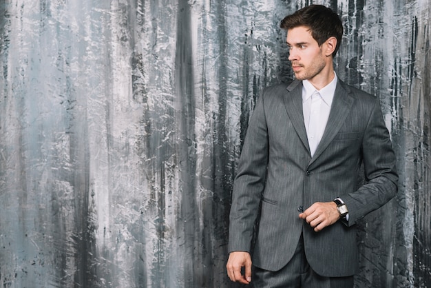 Stylish young businessman standing in front of wallpaper