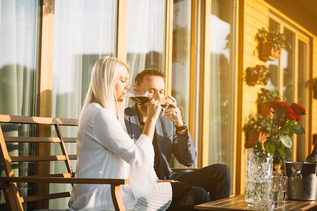 Stylish young couple sitting in patio drinking red wine