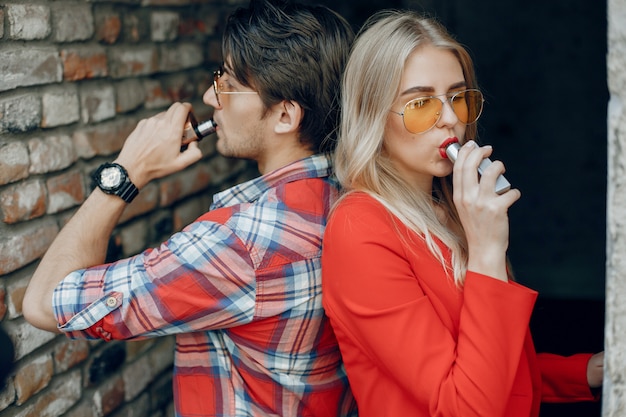 Free Photo stylish young couple with vape in a city