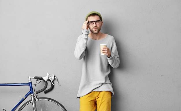 Stylish young man standing near bicycle