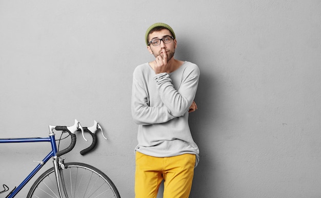 Stylish young man standing near bicycle