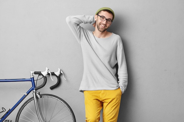 Free photo stylish young man standing near bicycle