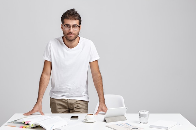 Free photo stylish young man standing near desk